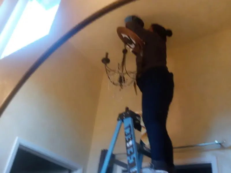 Electrician installing a chandelier in a Matteson residence